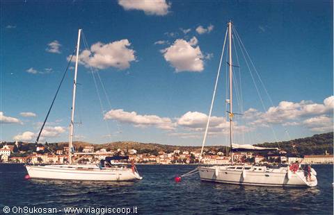 Two white sailboats anchored in front of the small Adriatic coastal town