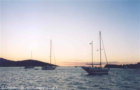 Sailboats anchored at dusk, dark hills on the sea horizon
