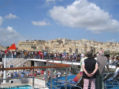 Passengers on the ship deck watch the stone houses of Valletta