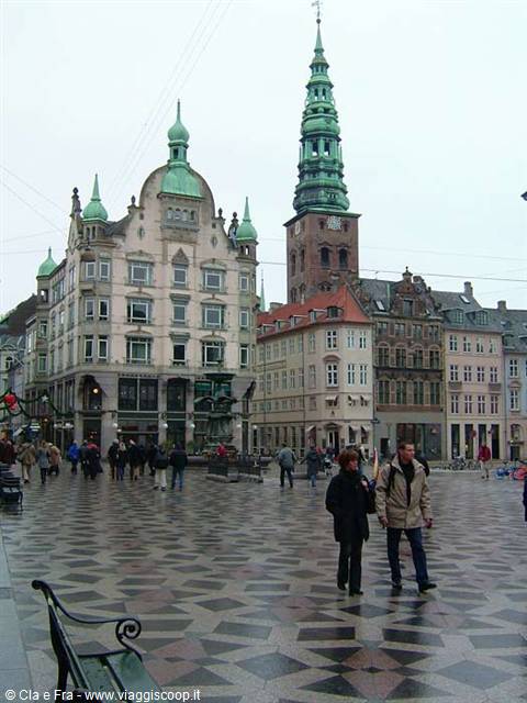Tourists walk on checkered pavement of Højbro Plads, Nikolaj tower