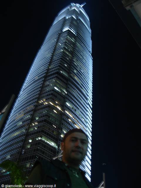 Tourist standing beneath the illuminated Two IFC skyscraper at night in Hong Kong