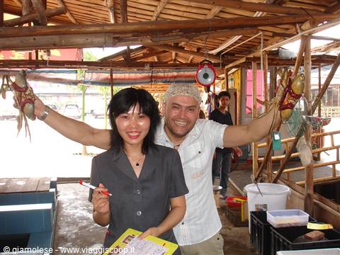 Smiling tourist holds up two large crabs in a wooden seafood market