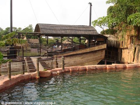 Wooden pirate ship among palms by a green pond in a themed park