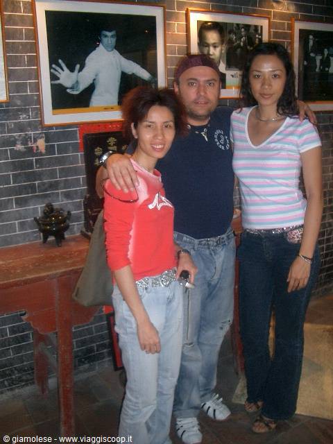 Tourist posing with two women beside Bruce Lee portraits in a museum