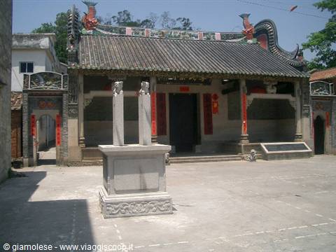 Chinese temple with tiled roof, stone pillars and paved courtyard under sunlight