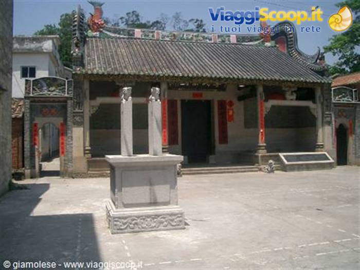 Chinese temple with tiled roof, stone pillars and paved courtyard under sunlight