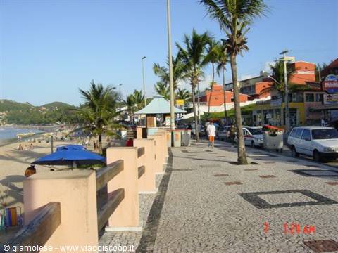Seaside promenade with palms and Portuguese stone pavement, lifeguards on beach