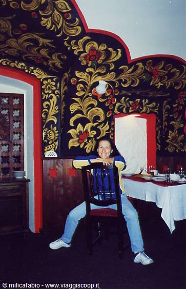 Woman sitting backwards on a chair in a room with floral painted vaults
