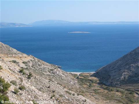 Rocky valley on Pag island, blue sea with small islet offshore