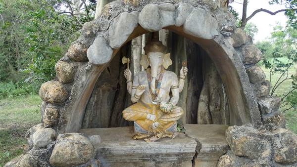 Ganesha stone statue sheltered by a rock arch among greenery