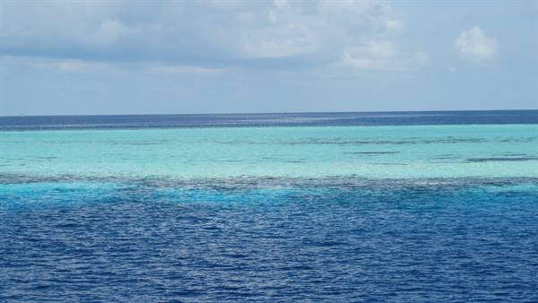 Turquoise lagoon with shallow coral reef under a cloudy sky