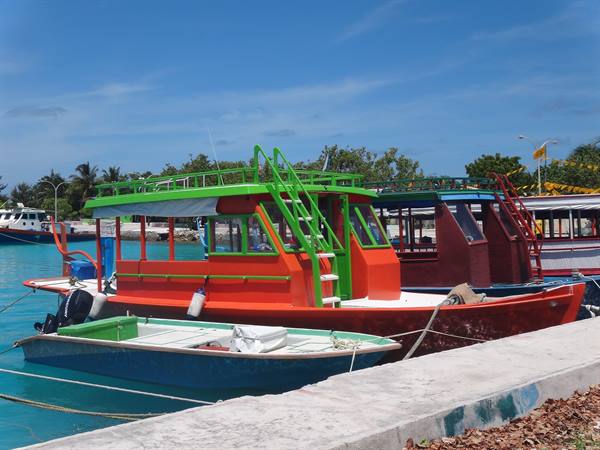 Colorful red and green boats moored at the concrete pier, turquoise water