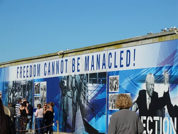 Visitors before Mandela mural reading Freedom Cannot Be Manacled, Robben Island