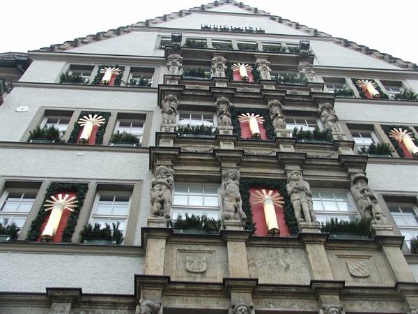 Facade with statues and illuminated Christmas candles between windows