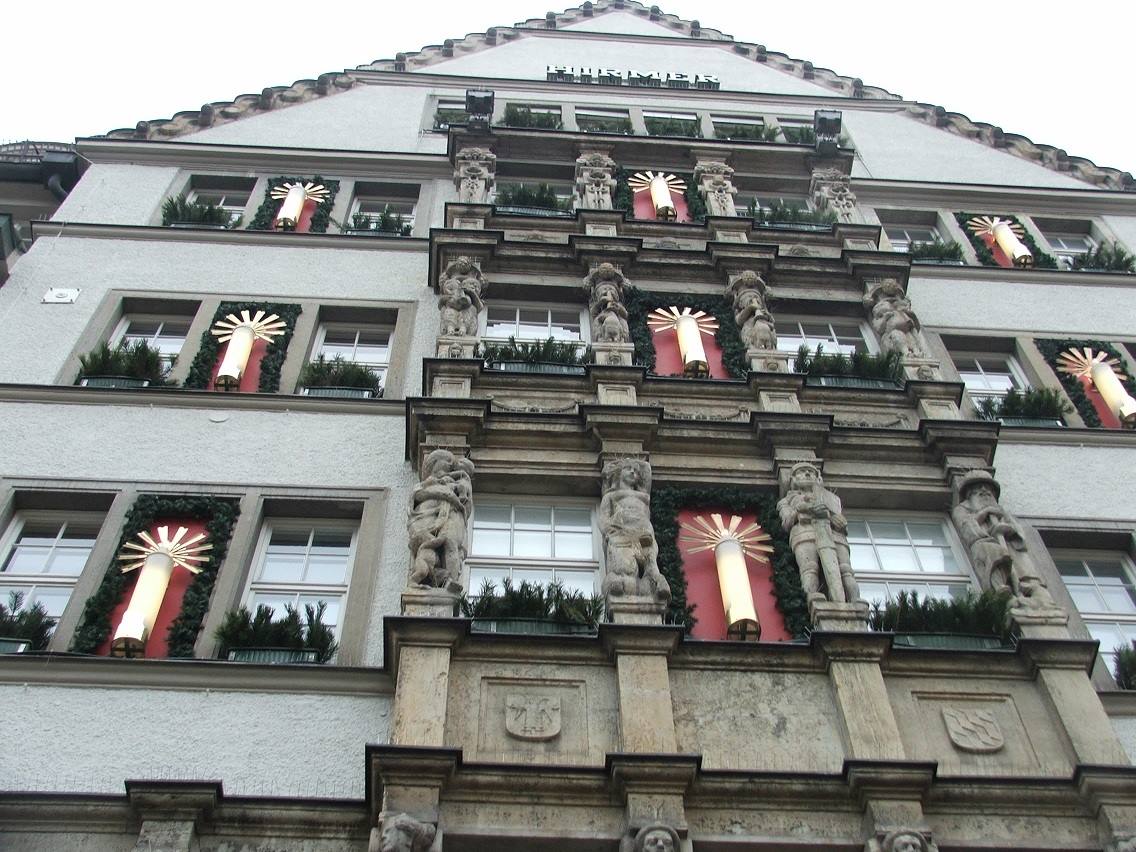 Facciata con statue e candele natalizie illuminate tra le finestre