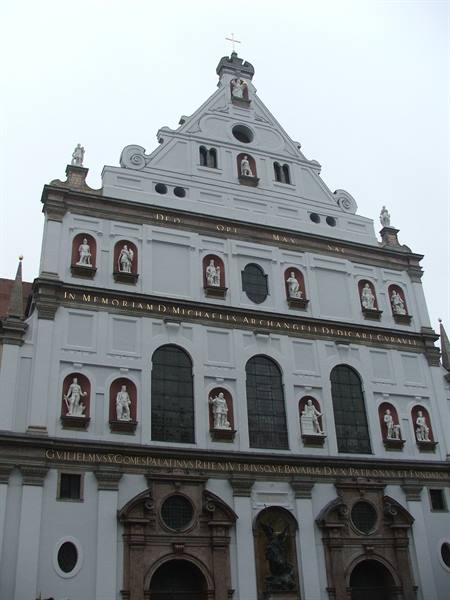 White facade of St. Michael's Church in Munich with statue niches under grey sky