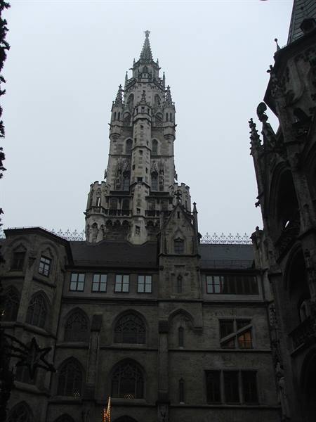 The neo-Gothic tower of Munich's Neues Rathaus rises above the facade under a grey sky