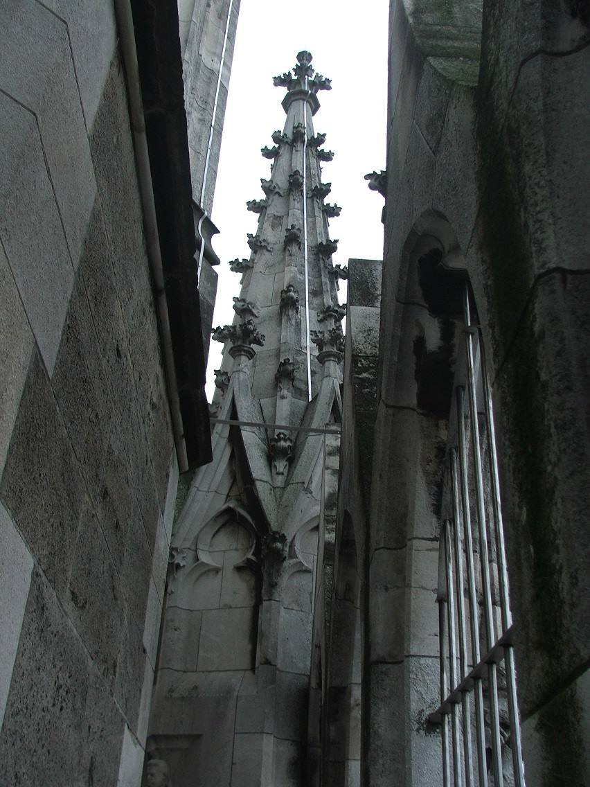 Guglia gotica in pietra tra marmi del Duomo di Milano, cielo grigio
