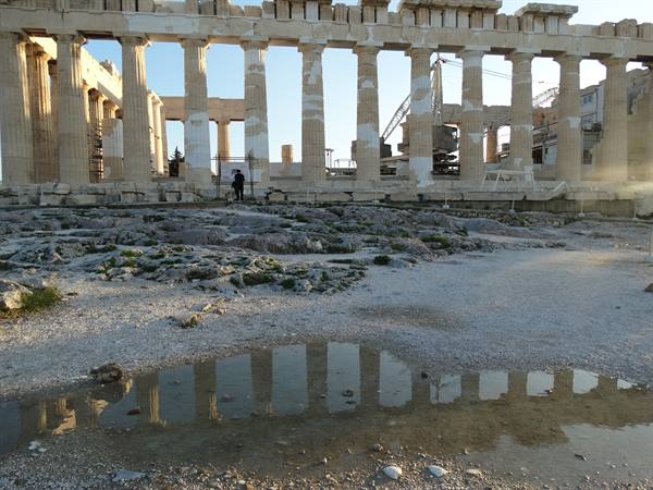 Marble colonnade of the Parthenon on the Acropolis, reflected in a puddle