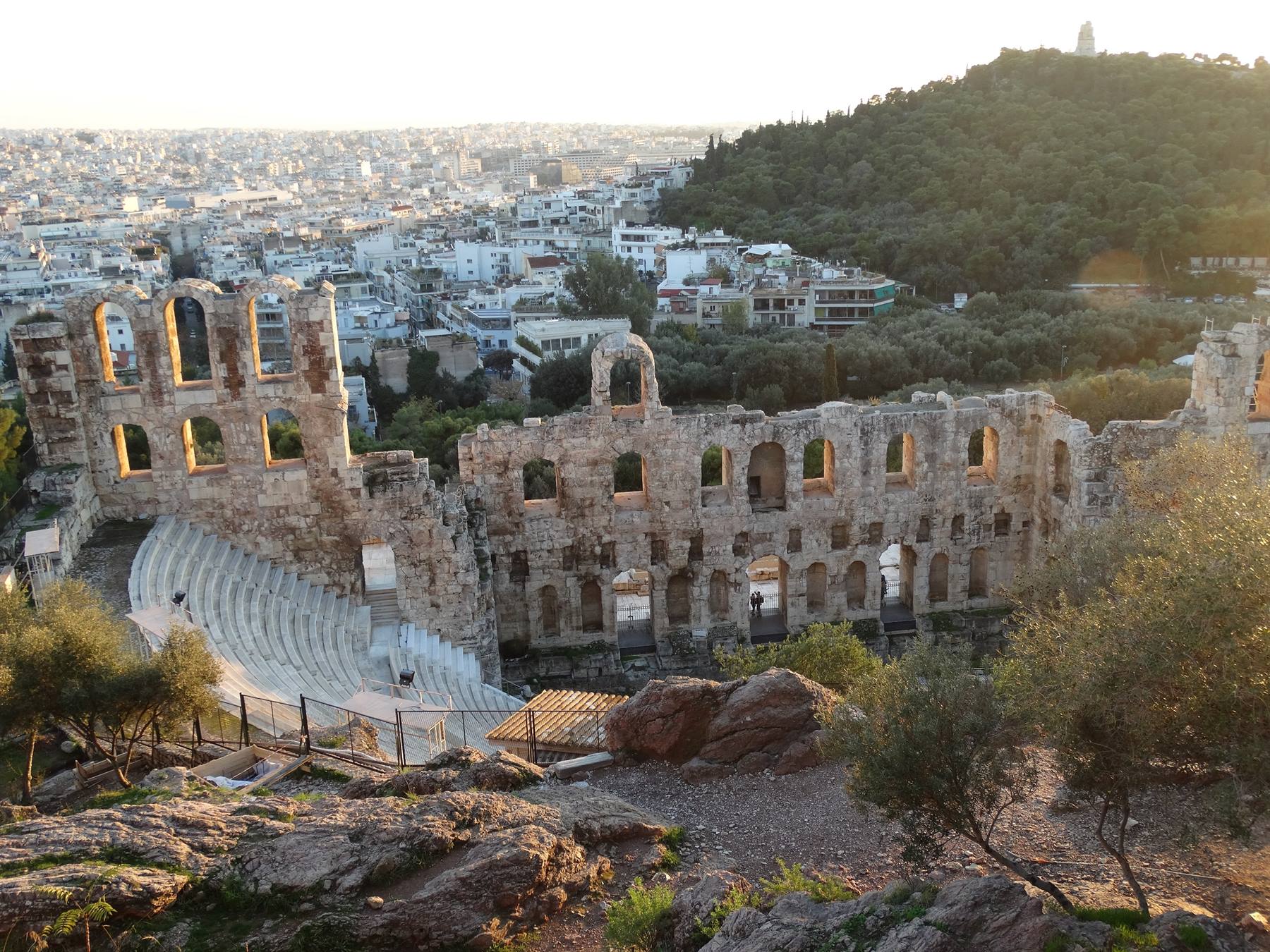 L'Odeon di Erode Attico ad Atene, gradini in marmo tra rovine di pietra e collina verde