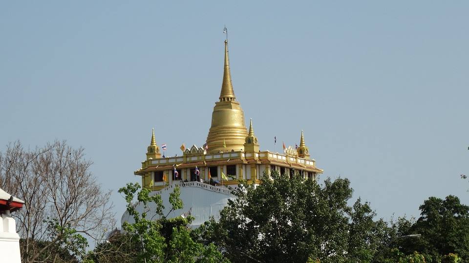 Stupa dorato sul Monte d'Oro a Bangkok, sopra il manto bianco, tra gli alberi