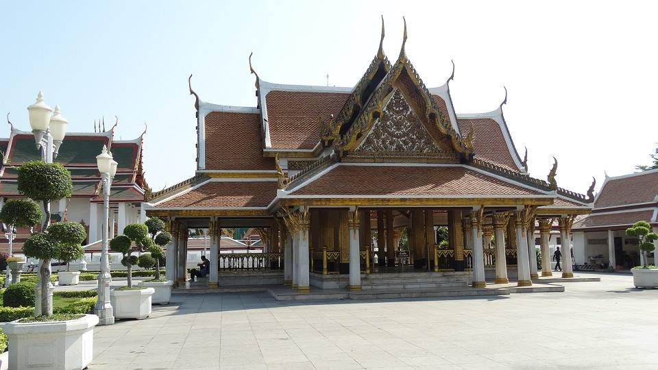 Padiglione thai con tetto dorato e tegole rosse, pilastri bianchi, cortile lastricato