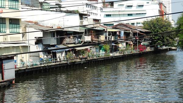 Wooden houses along a Bangkok canal, power lines, daylight