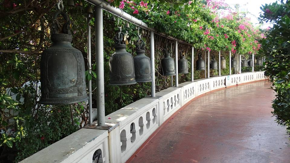 Campane di bronzo appese al parapetto del Golden Mount a Bangkok, tra bouganville