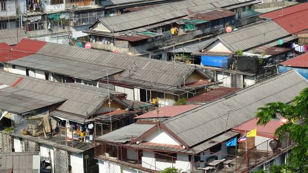 Corrugated metal roofs over dense housing with flags, daylight