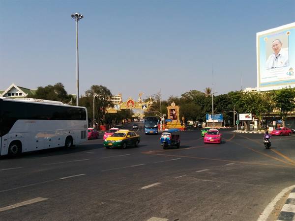 Bangkok intersection: tuk-tuk, pink taxis and bus under the king's billboard