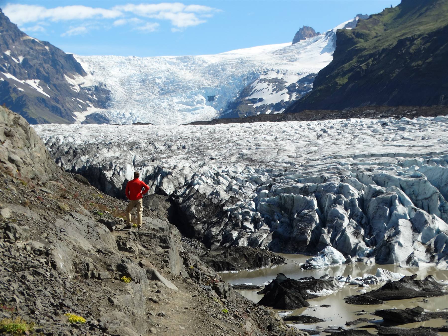 Escursionista in giacca rossa davanti alla lingua glaciale di Svínafellsjökull