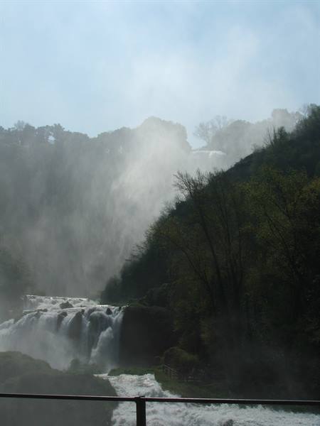 Marmore Falls wrapped in mist, rushing white water, metal railing in foreground