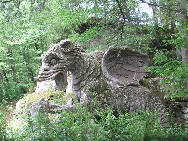 Winged dragon stone statue covered in moss among trees, Bomarzo