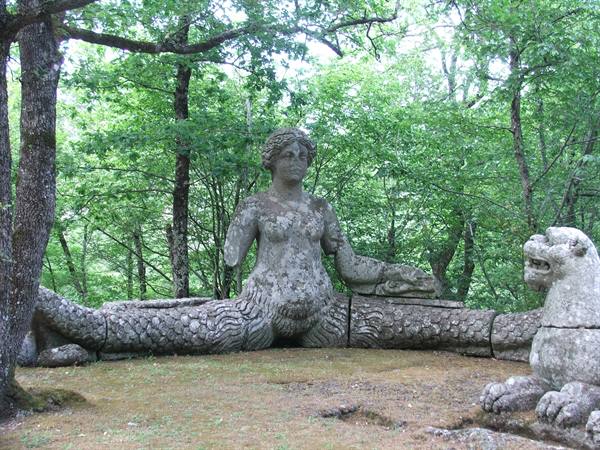 Stone mermaid statue among the trees of the Parco dei Mostri in Bomarzo