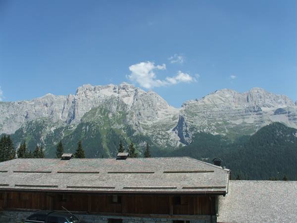 Wooden chalet roof with a car beneath Dolomite peaks