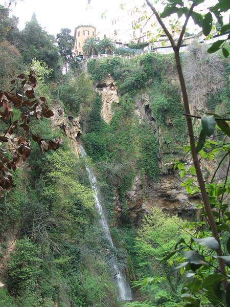 Waterfall on rocky cliffs at Villa Gregoriana, Tivoli, buildings above