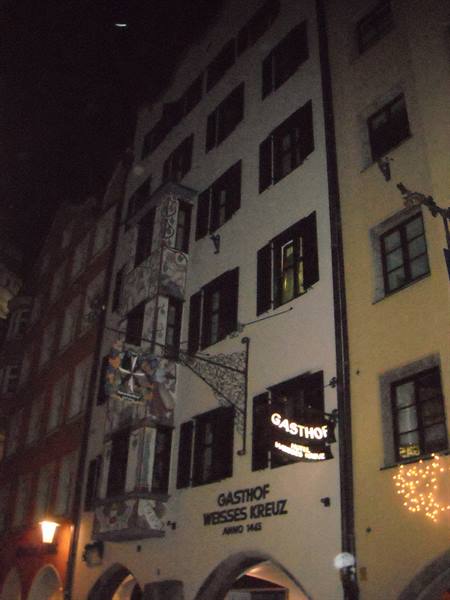 Night facade of Gasthof Weisses Kreuz, glowing sign and festive lights