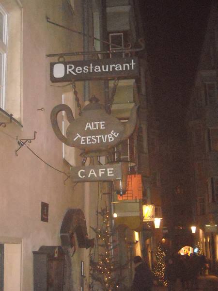 Teapot-shaped sign of the Alte Teestube restaurant in a lit night alley