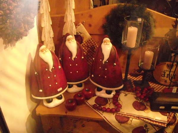 Three red ceramic Santa Clauses with candles on a wooden cabinet