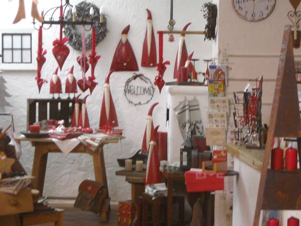 Red fabric Santa Claus figures and candles in a Christmas shop with welcome sign