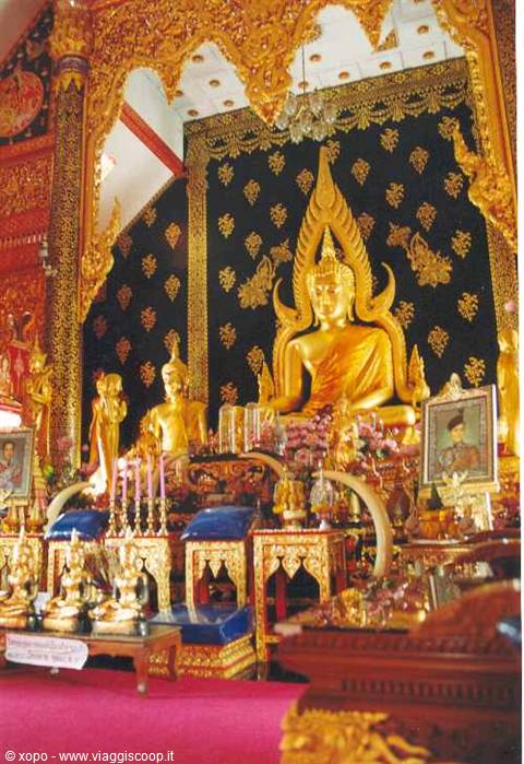 Large golden Buddha on temple altar with candles and offerings