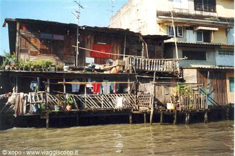 Wooden stilt houses along the river, laundry hanging from balconies