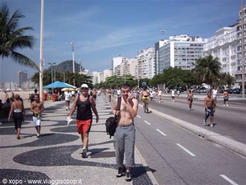 Copacabana wave-patterned boardwalk, tourists and cyclists under the sun