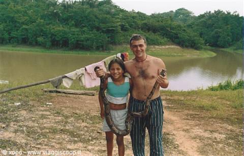 Tourist and girl holding a snake by an Amazon river