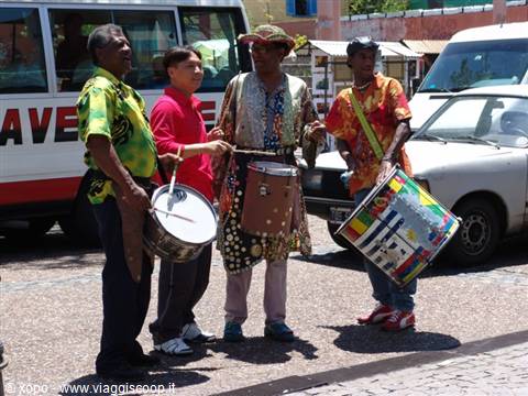 Four drummers in colorful shirts playing drums on a street