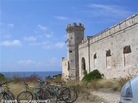 Bicycles parked in front of a stone fortress overlooking the sea