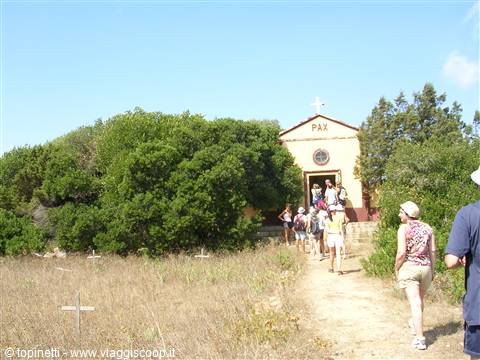 Visitors walk toward a small yellow church marked PAX
