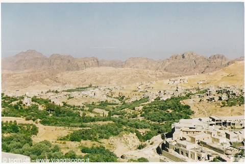 Stone houses among green trees with rocky mountains, Wadi Musa