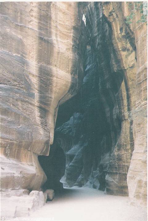 Wind-carved sandstone walls and sandy path inside the Siq of Petra