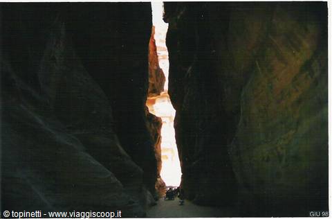 Tourists walk through the Siq of Petra, narrow gorge between carved rock walls